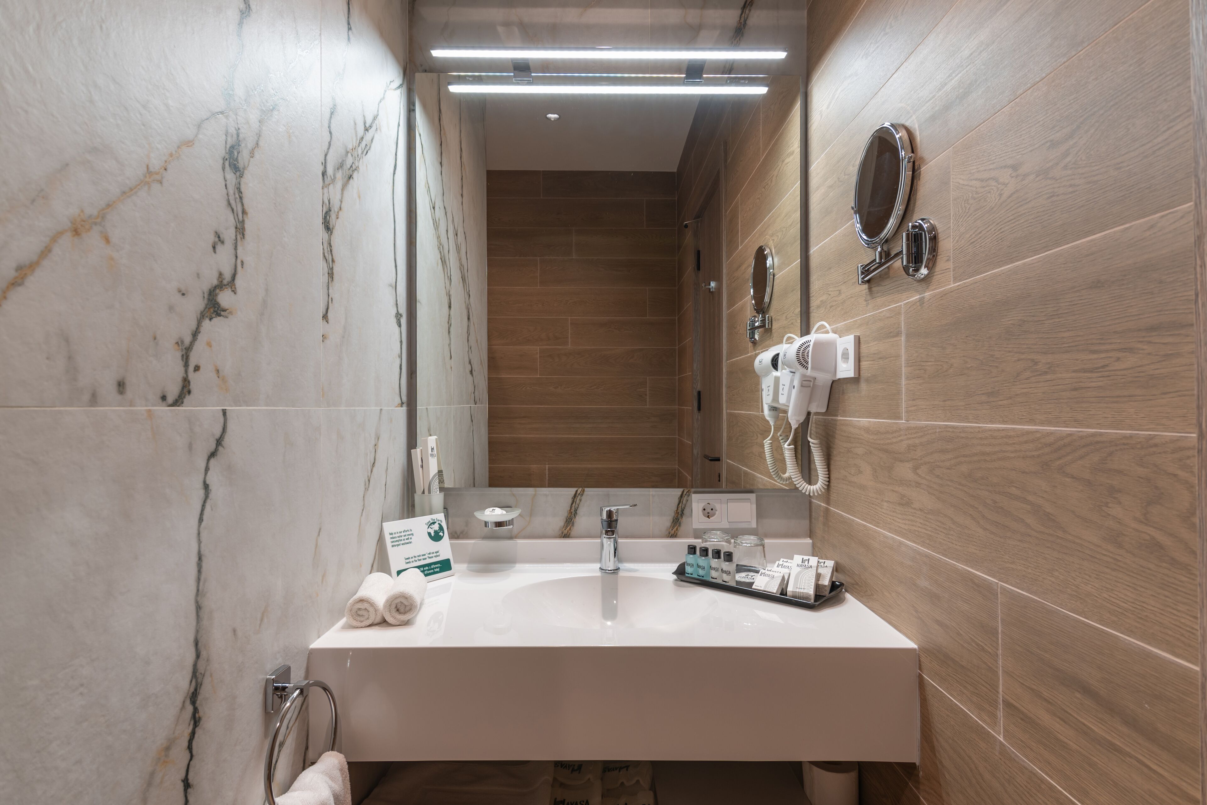 Un baño moderno con lavamanos de mármol, paredes de madera y un espejo.