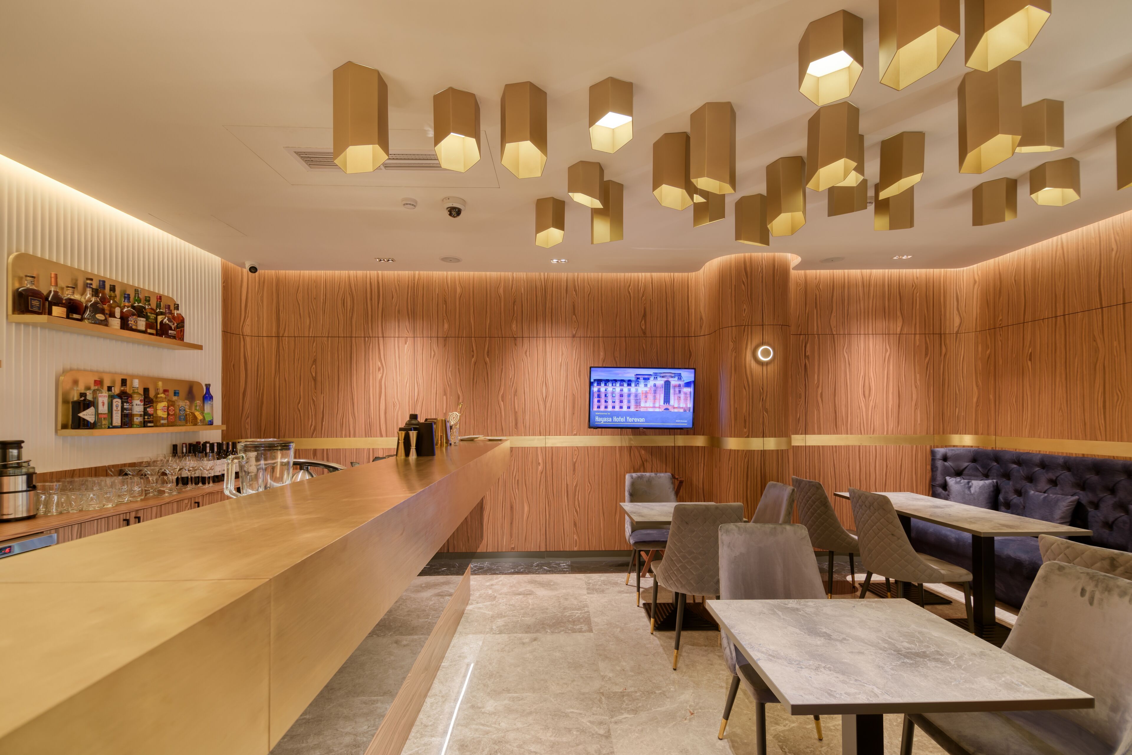 Un espace bar moderne avec un comptoir en bois, des sièges et un écran de télévision.