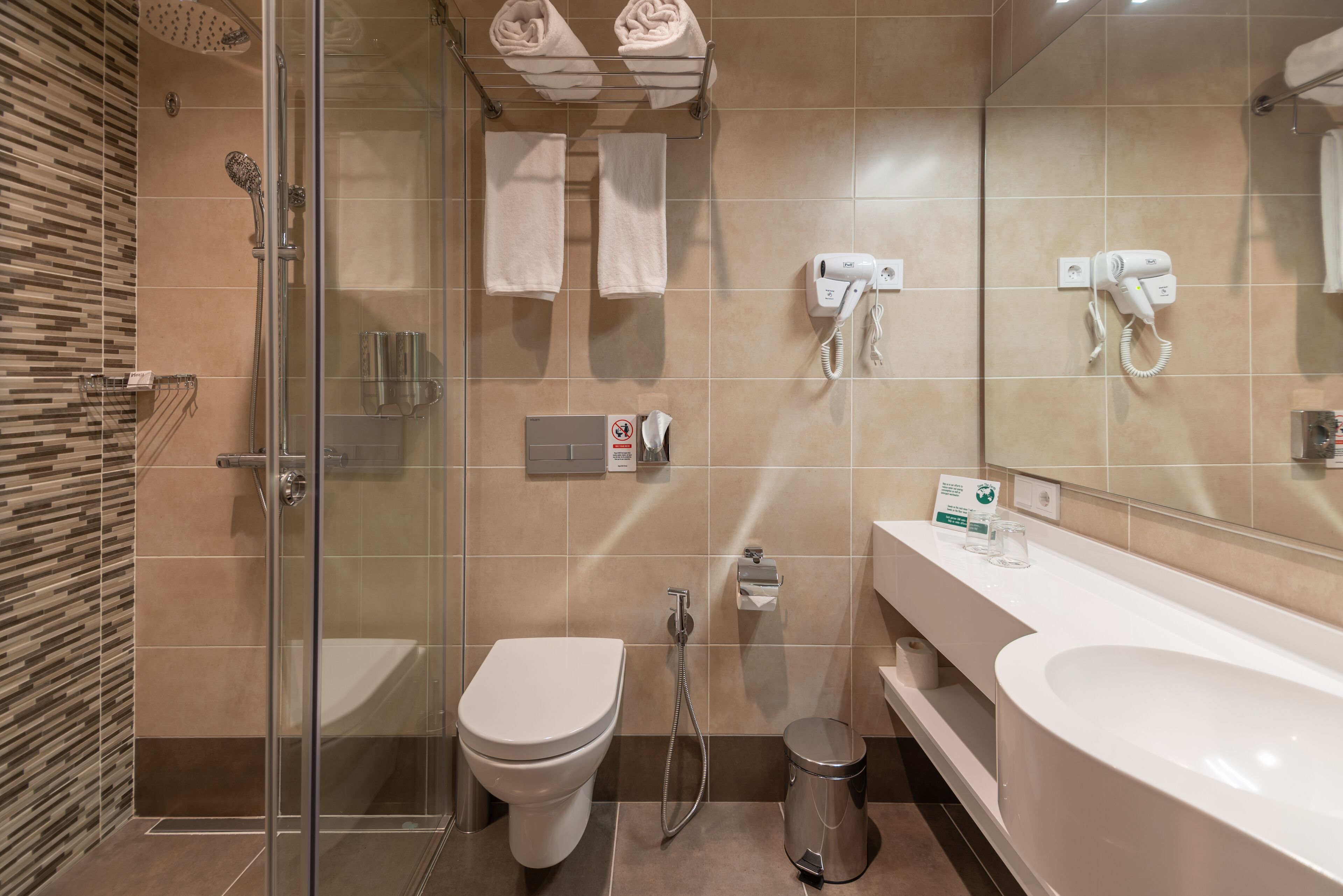Un baño moderno con ducha de vidrio, inodoro, bidé y lavamanos grande.