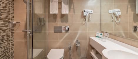 Un baño moderno con ducha de vidrio, inodoro, bidé y lavamanos grande.