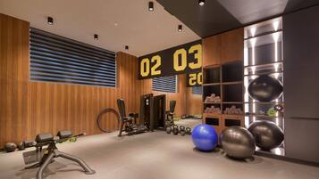 Een moderne sportschool met trainingsapparatuur, een digitale klok en een muur met opslagplanken.
