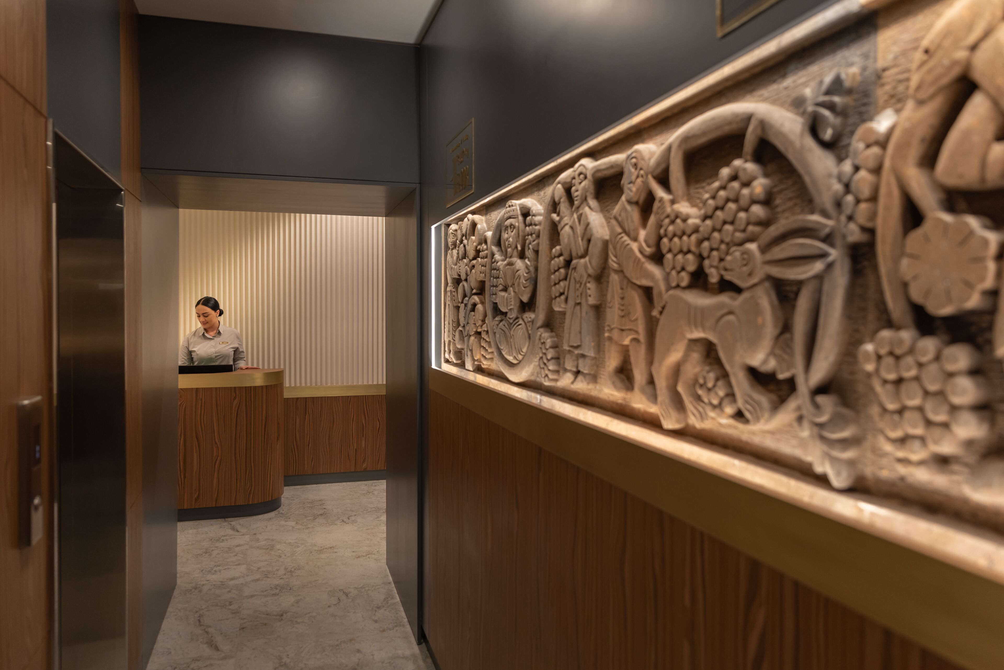 A reception area with a receptionist desk, a wooden reception desk, and a wall with a detailed carving.