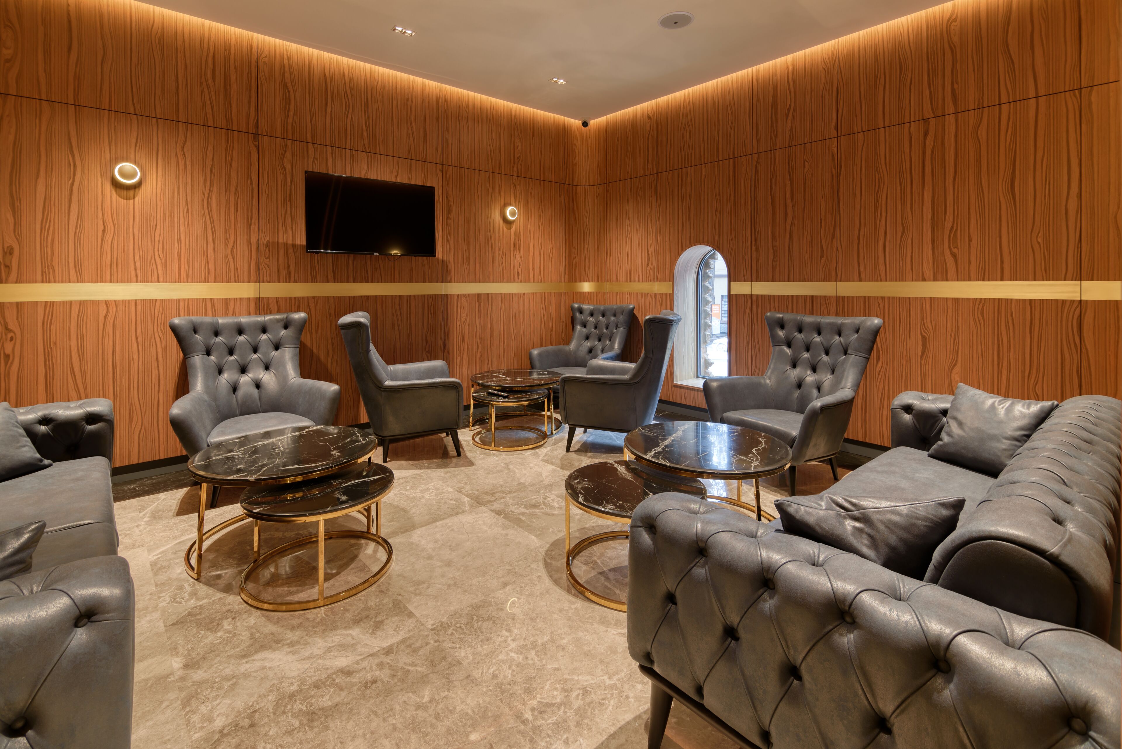 Een moderne lounge met leren banken, fauteuils en een marmeren salontafel.