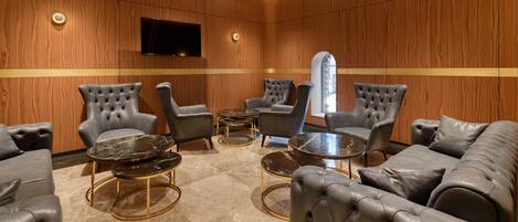 Een moderne lounge met leren banken, fauteuils en een marmeren salontafel.