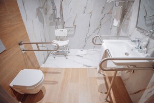 Een badkamer met toilet, handgrepen, douche en wastafel.