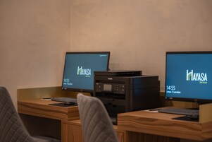 Een werkplek met twee schermen waarop het Hayasa logo staat, een Canon printer en een houten bureau.
