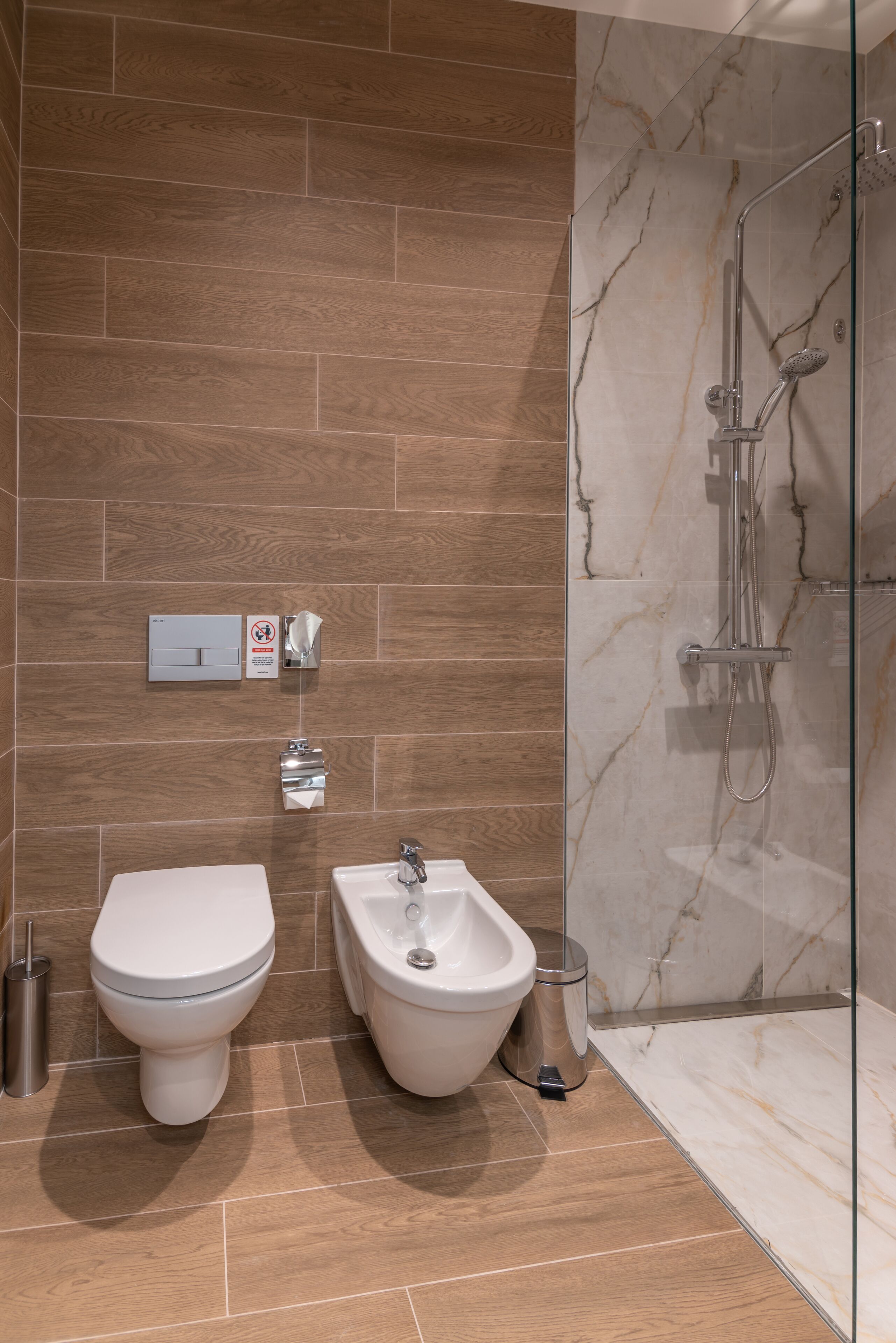 A modern bathroom with a bidet, toilet, and shower.