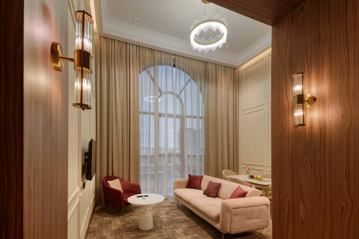 A spacious living room with a large window, a chandelier, and a modern sofa.
