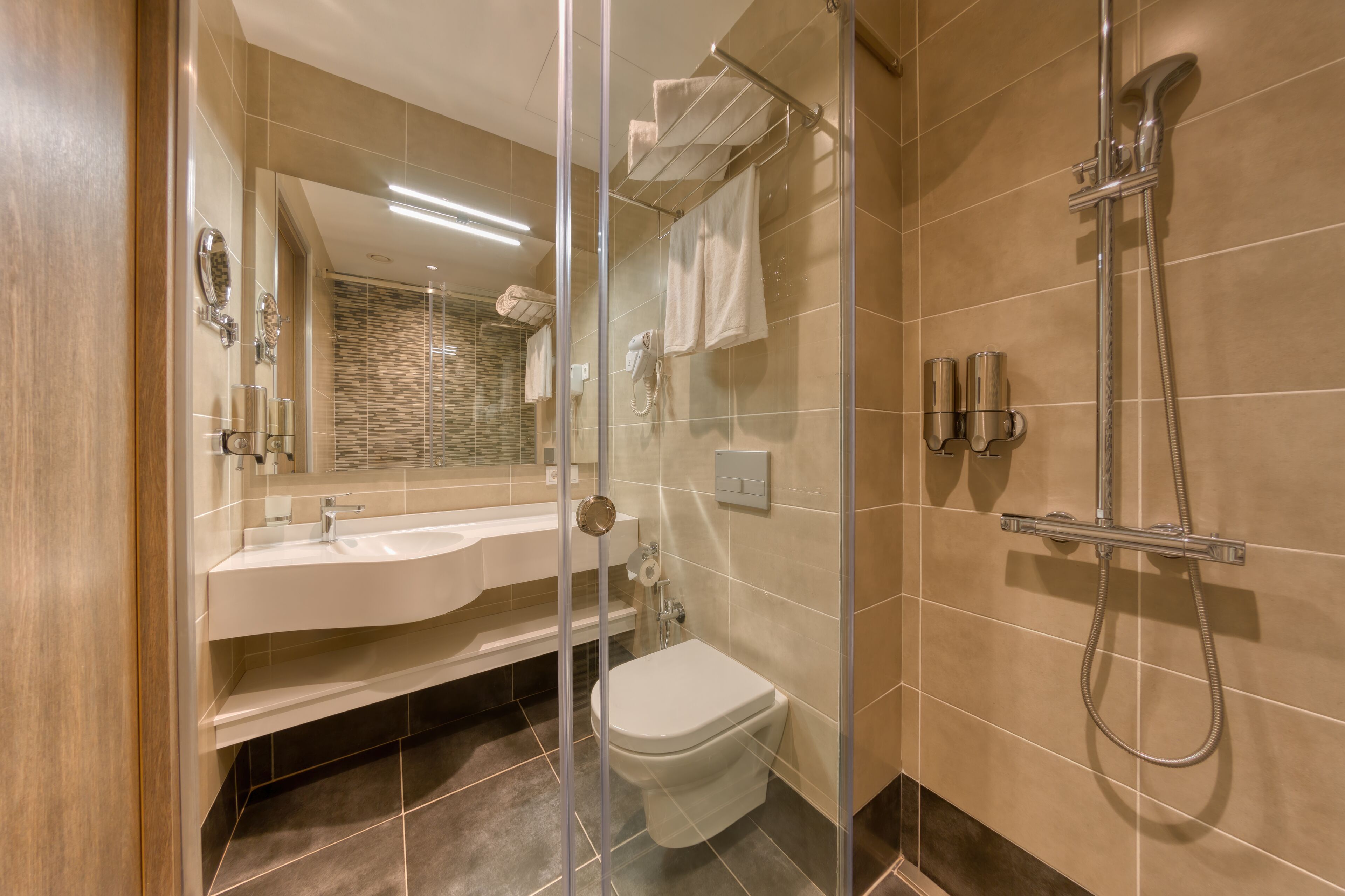 A modern bathroom with a glass-enclosed shower, a white sink, and a toilet.