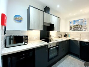Une cuisine moderne avec des meubles de couleur noire, un four à micro-ondes, un four traditionnel et un évier.