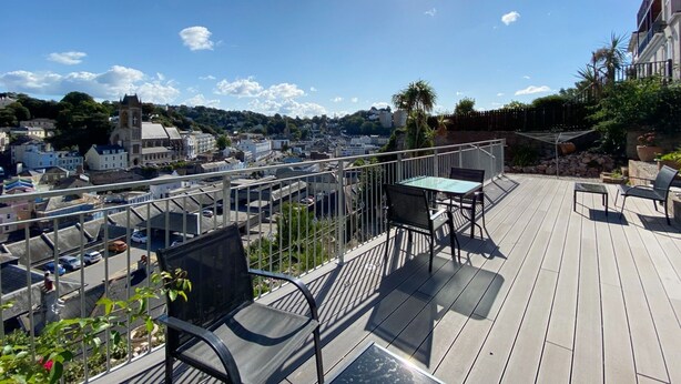 A deck with outdoor furniture overlooking a town. - Spacious, one bedroom, pet friendly apartment with large terrace overlooking the town. (Torquay)