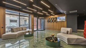 Een moderne lobby met een gebogen bank, een ronde salontafel en een grote televisie aan de muur.