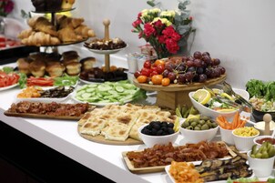 Un bufé con diversos alimentos, como pan, carnes, quesos y frutas.