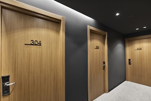Un pasillo con tres puertas de madera identificadas con los números 304, 305 y 306.