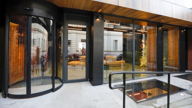Moderne gevel met glazen deuren, een metalen leuning en een zicht op het interieur.