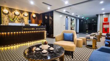 Een moderne hotellobby met een receptiebalie, een zithoek en een vloer met een patroon.