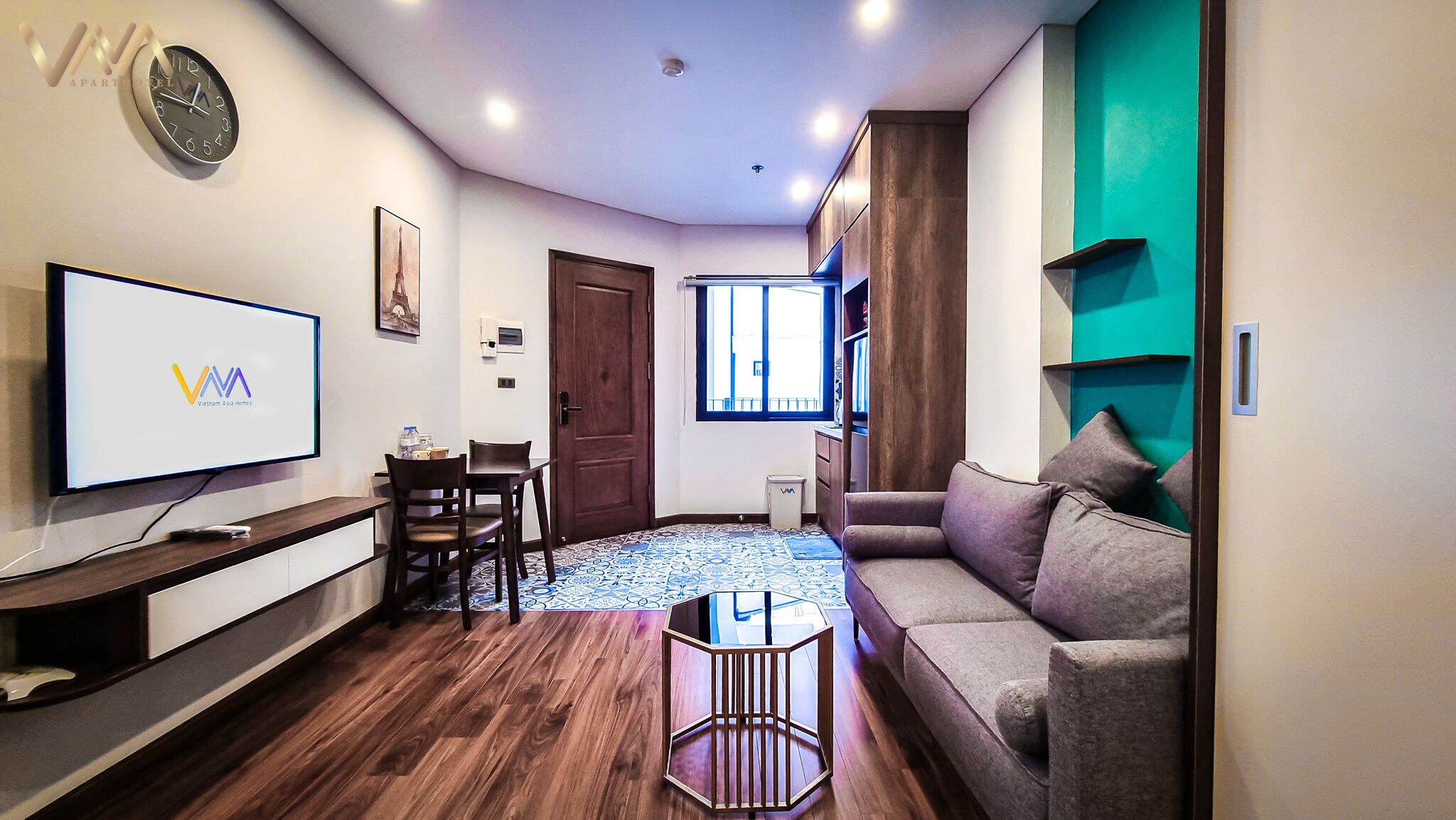 Una sala de estar moderna con televisor, muebles de madera, un sofá, una mesa de centro y un tapete estampado.