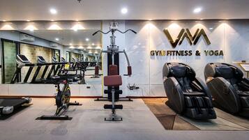 Ein Fitnessraum mit Trainingsgeräten, Laufband und Massagesessel.