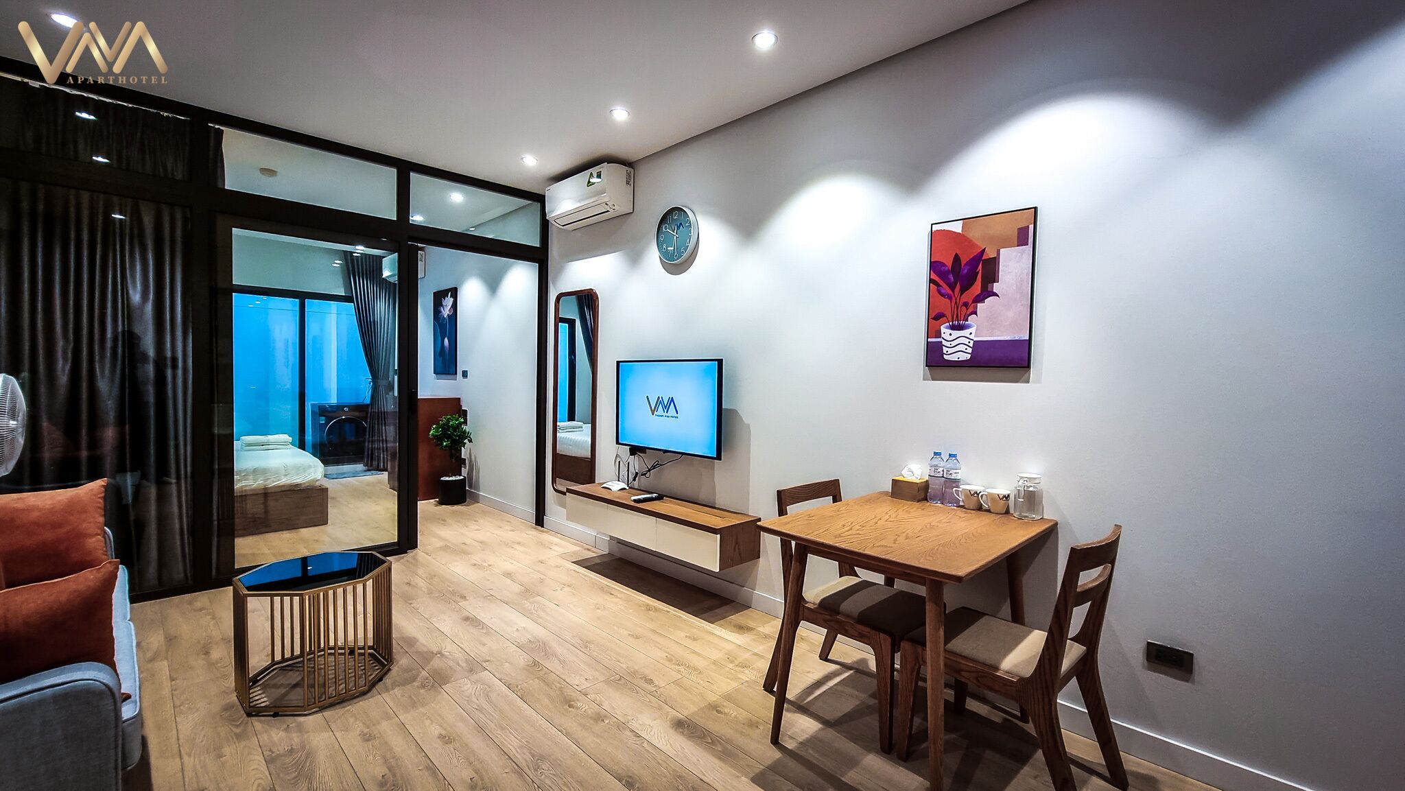 A modern apartment with a dining area, a TV, and a large window.