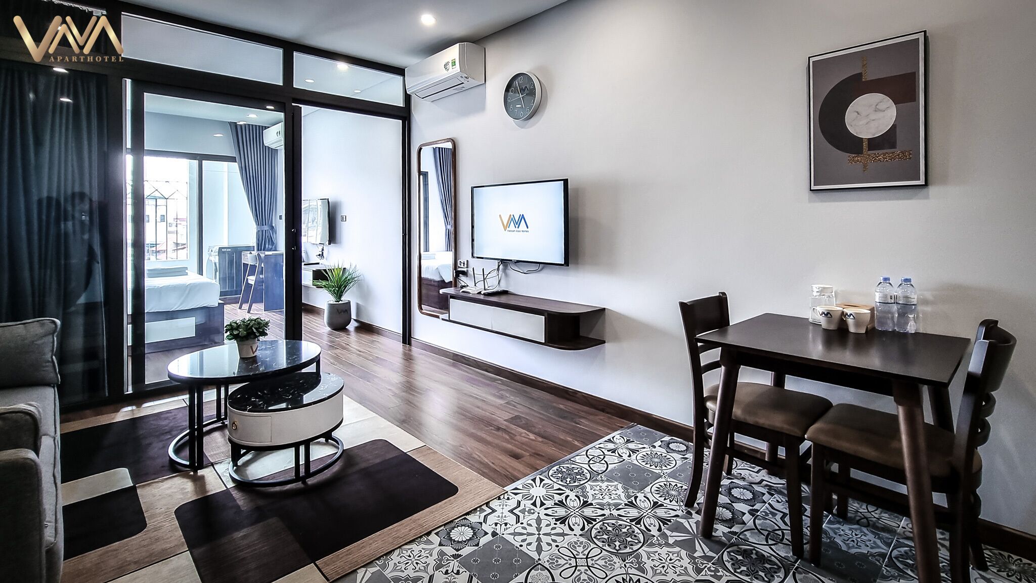 Ein modernes Hotelzimmer mit Essbereich, einem an der Wand montierten Fernseher und Blick durch das große Fenster nach draußen.