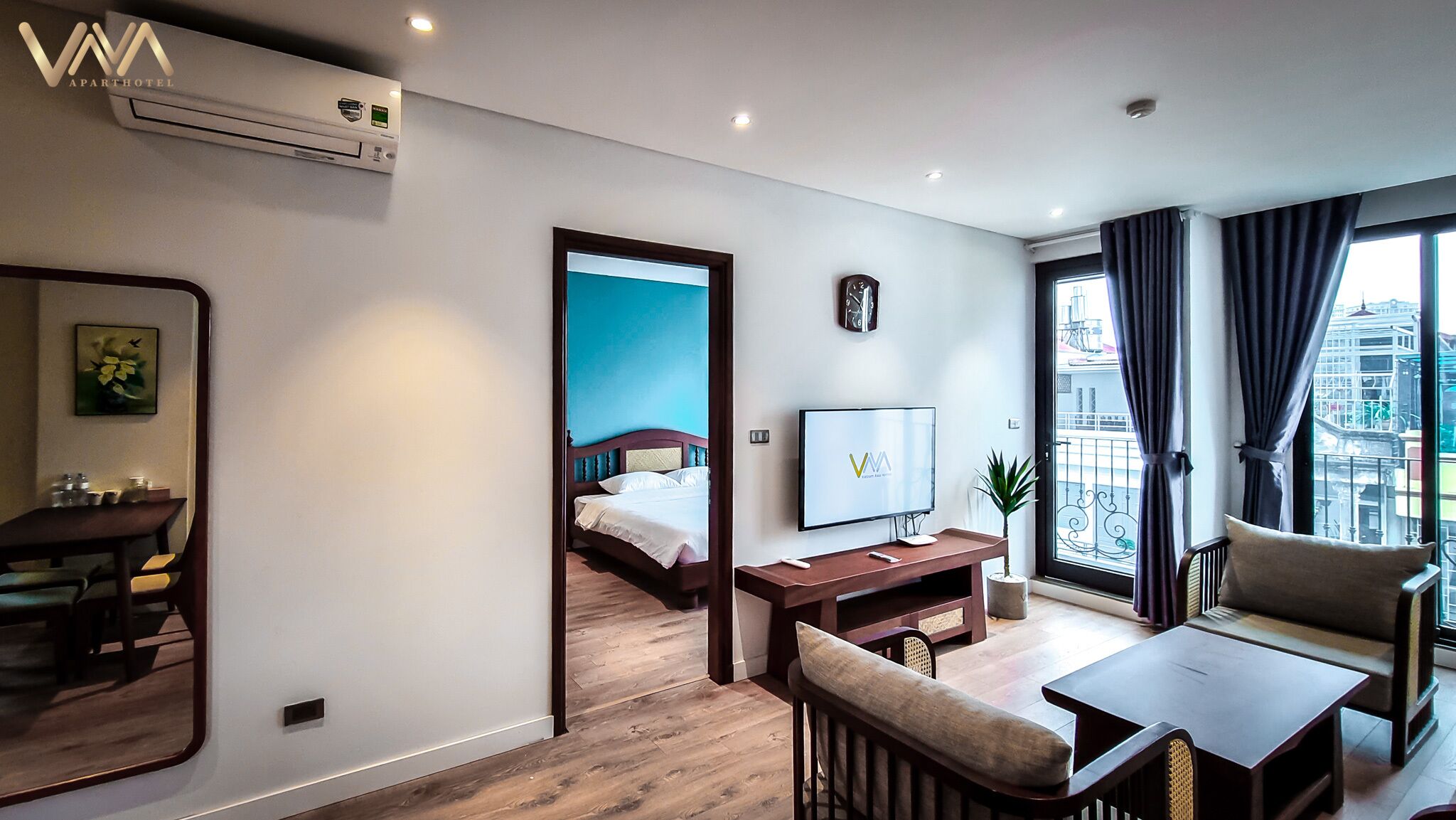 A modern hotel room with a bed, a desk, a TV, a chair, and a balcony with a view.