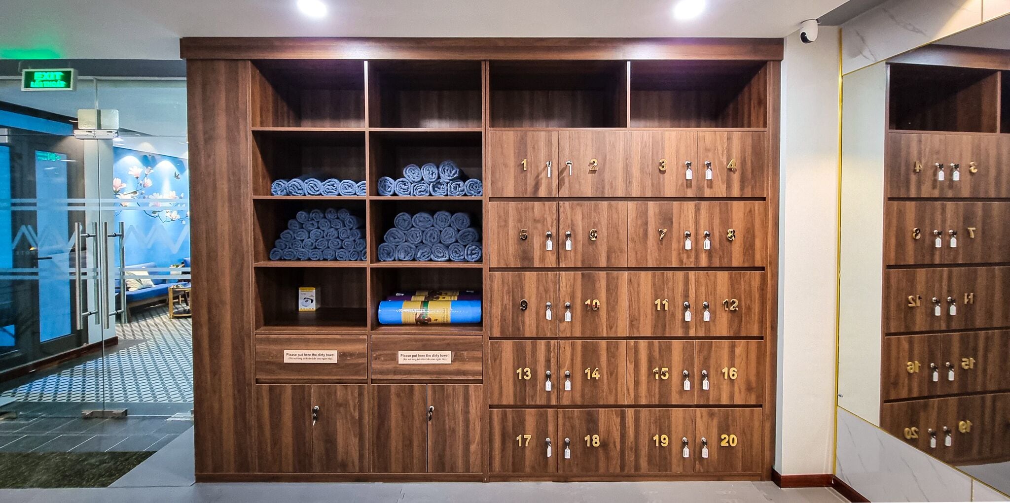 Une chambre d’hôtel dotée d’une grande armoire en bois comportant plusieurs compartiments, dont certains contiennent des serviettes et des articles de toilette.