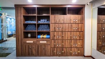 Une chambre d’hôtel dotée d’une grande armoire en bois comportant plusieurs compartiments, dont certains contiennent des serviettes et des articles de toilette.