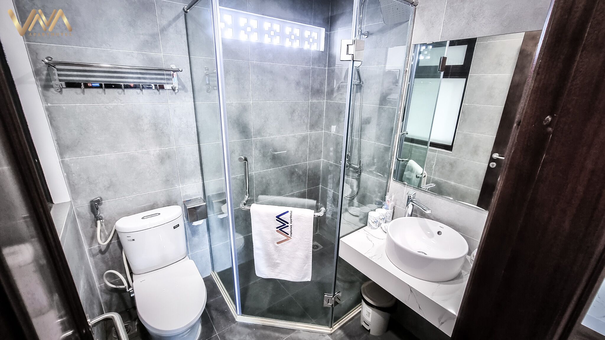 A modern bathroom with a glass-enclosed shower, a toilet, and a sink with a mirror above it.