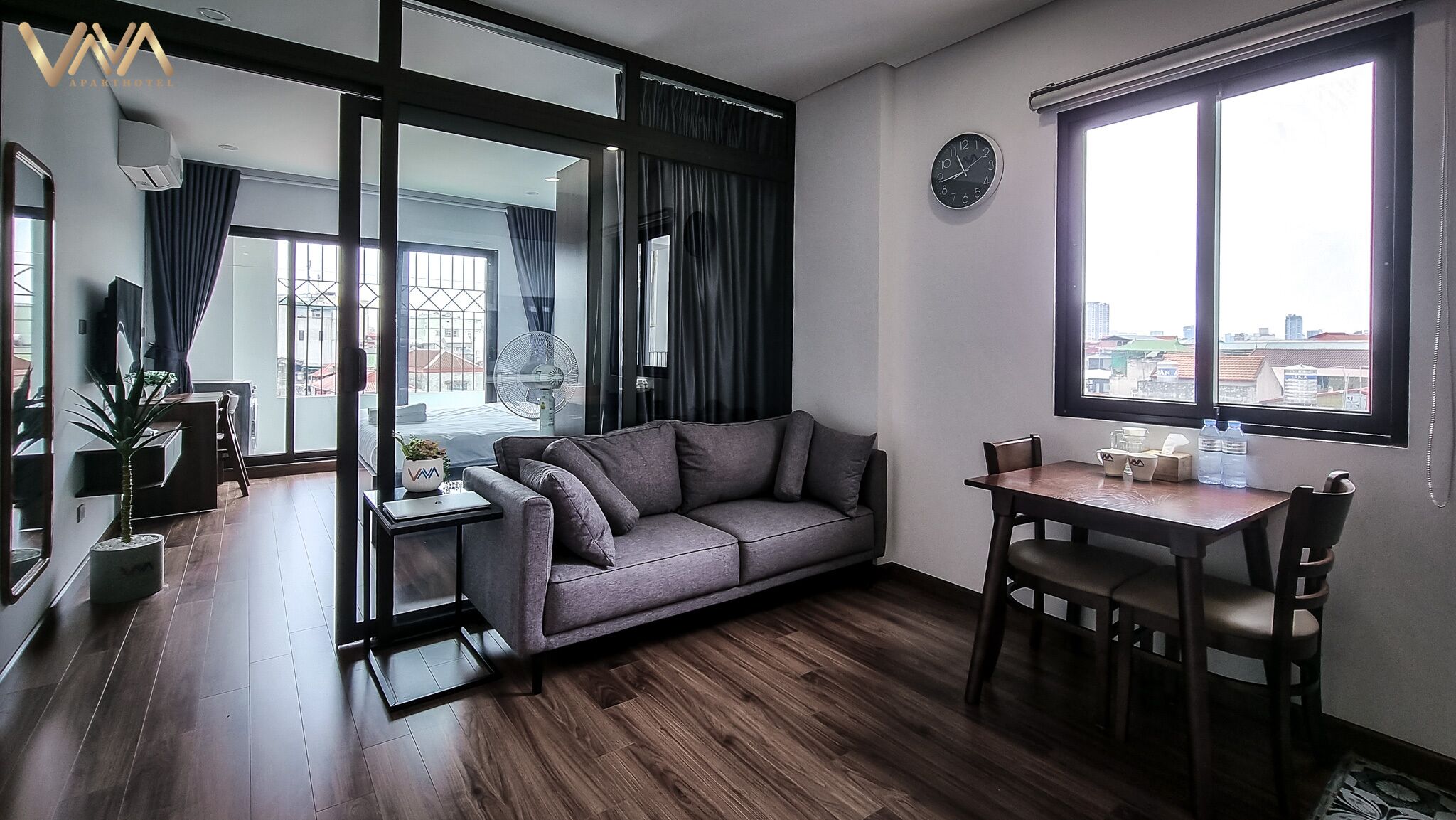 A modern living room with a sofa, a dining table, and a large window.