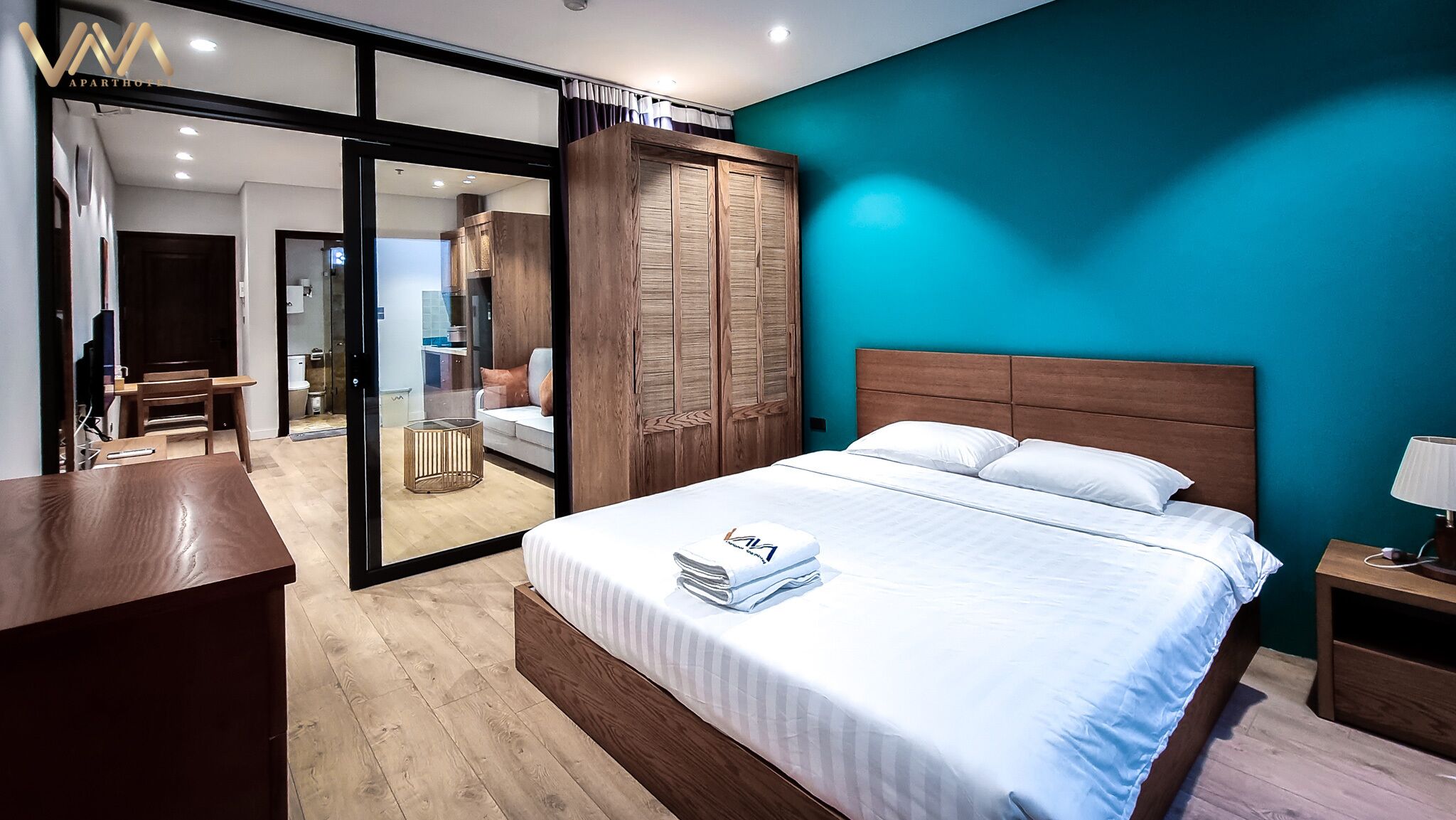 Un dormitorio moderno con una cama grande, un armario de madera y una puerta de cristal que da a un balcón.