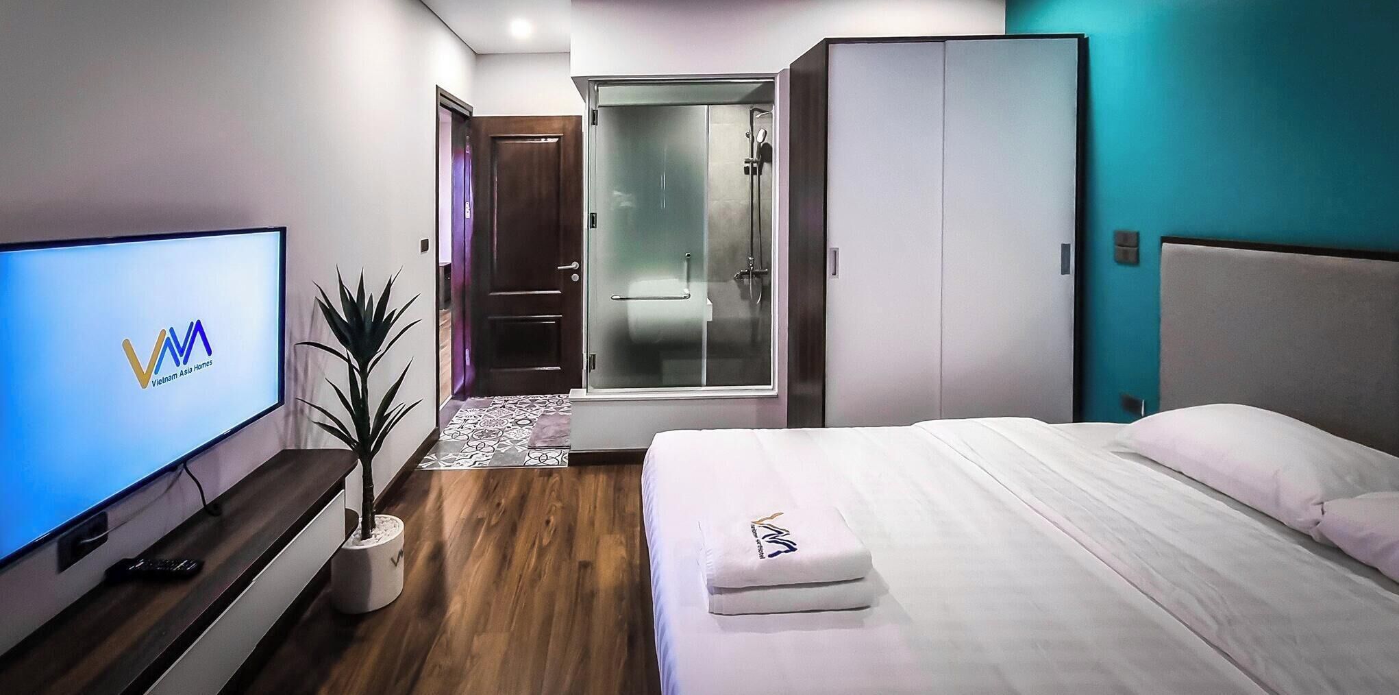 A hotel room with a bed, a TV, a plant, a walk-in closet, and a shower.