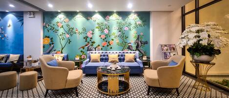 A modern living room with a blue sofa, two armchairs, a round coffee table, and a patterned floor.