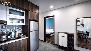 Ein kleines Hotelzimmer mit Küchenzeile, einem Bett, einer Essecke und einem Spiegel.