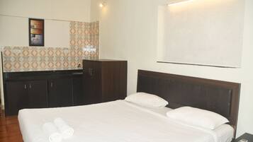 A hotel room with a bed, a wardrobe, and a small table.