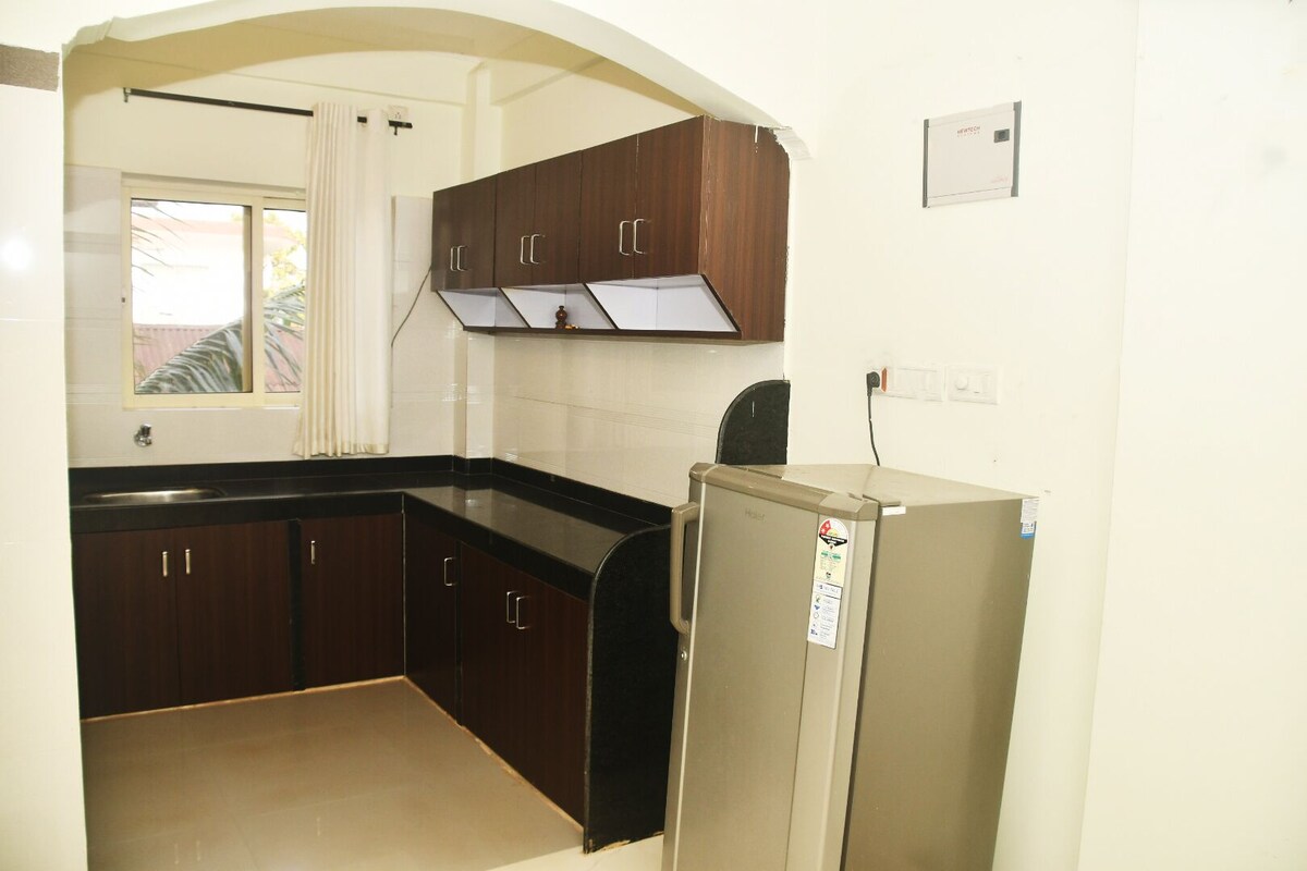 A compact kitchen with dark wooden cabinets, a built-in sink, and a refrigerator.