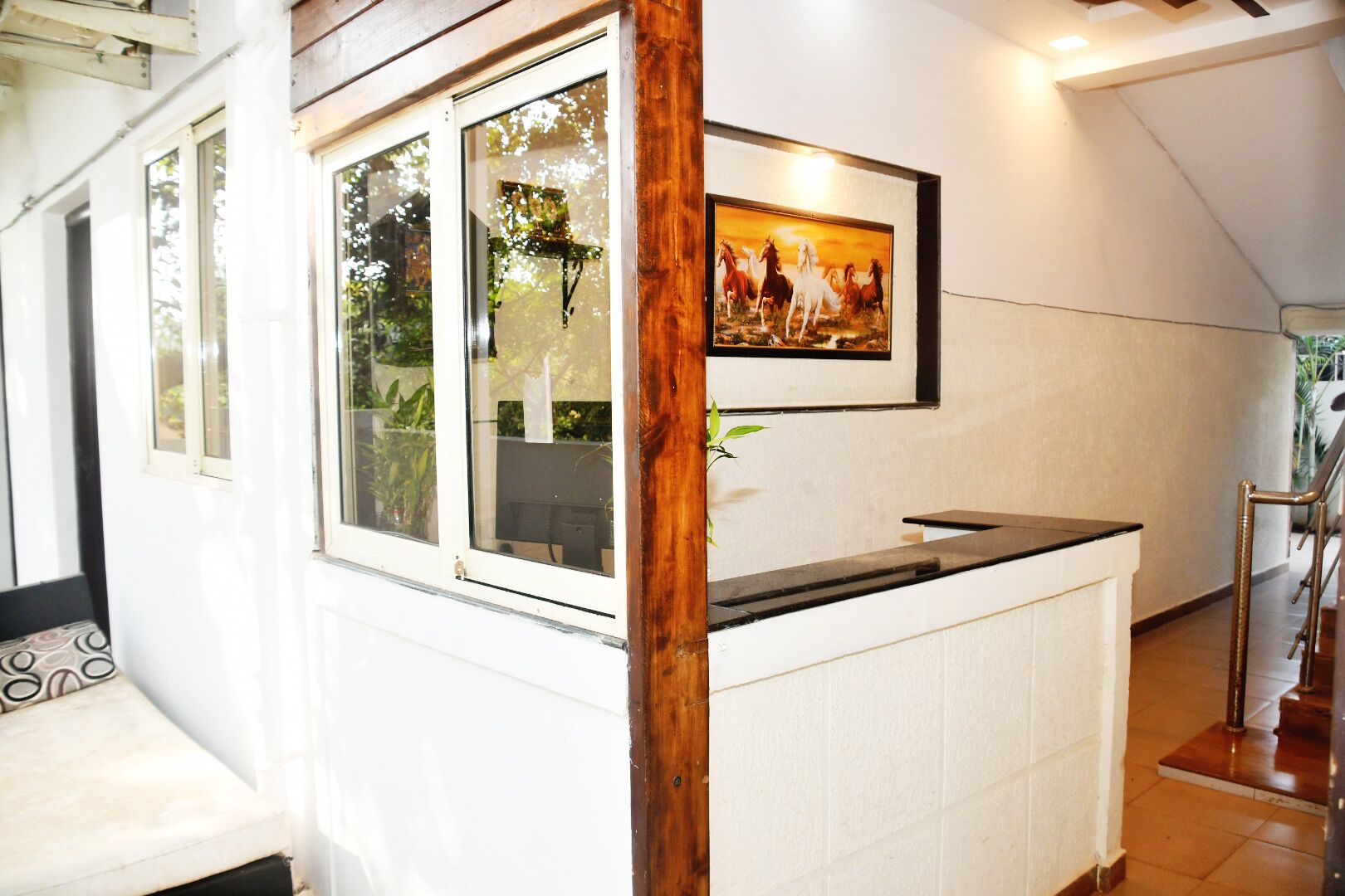 A reception area with a wooden post, a framed painting of horses, and a counter.