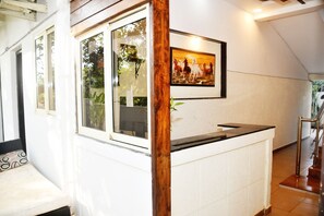 A reception area with a wooden post, a framed painting of horses, and a counter. - Klase Homep (Arambol)