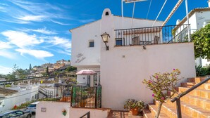 A white building with a balcony, a staircase, and a parked car. - Villa Caritas Punta Lara by Casasol (Nerja)