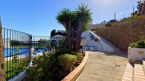 A pool area with a stone wall, a staircase, and a clear blue sky. - Villa Caritas Punta Lara by Casasol (Nerja)