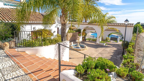 A courtyard with a fountain, palm trees, and a tiled patio. - Villa Caritas Punta Lara by Casasol (Nerja)