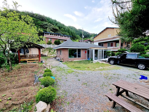 A residential area with a house, a wooden deck, and a gravel driveway.
