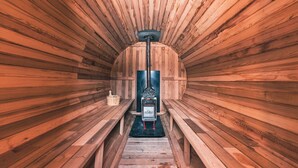 A sauna with wooden benches and a central heating unit. - From P (Hakuba)