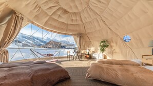 A tented room with two beds, a small table, and a view of mountains. - From P (Hakuba)