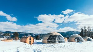 A snow-covered landscape with yurts and wooden cabins. - From P (Hakuba)