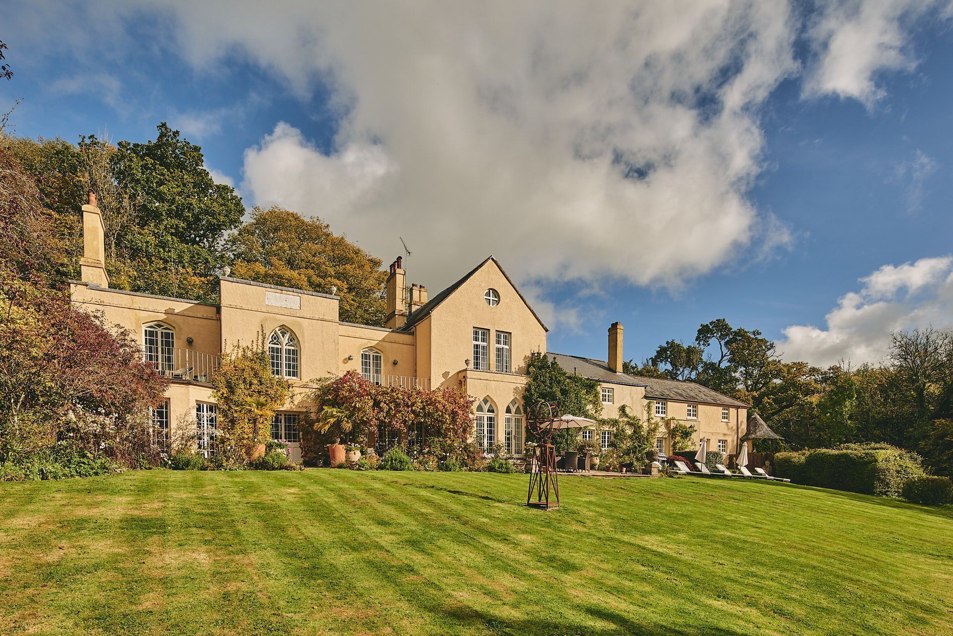 A large, two-story building with a symmetrical facade, multiple windows, and a well-maintained lawn with sun loungers.