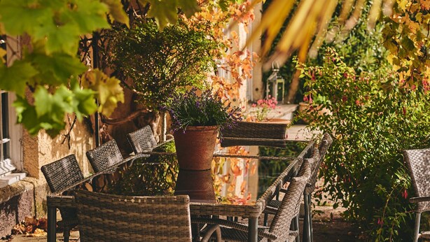Wicker chairs and a table in an outdoor setting with a pergola overhead.