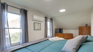 A bedroom with a bed, a dresser, a television, and an air conditioning unit. - Cozy Historic Wakefield Home Close to Beaches (South Kingstown)