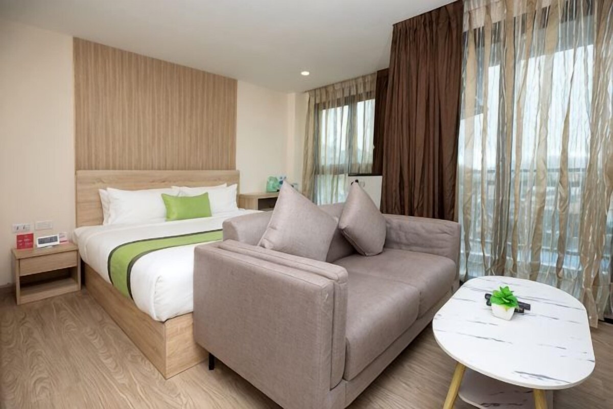 A hotel room with a bed, a sofa, a small table, and a view of the outdoors.