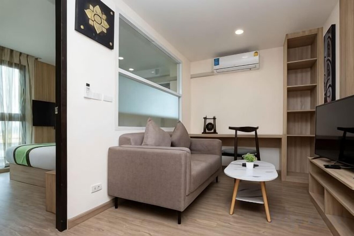 A modern living room with a sofa, a small round table, a television, and a bookshelf.