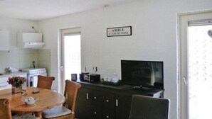 En matplats med ett runt bord, stolar, en tv och en skylt på väggen.
